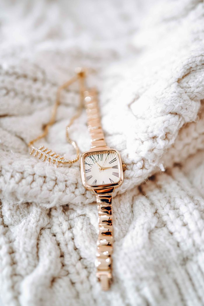 Close-up of a stylish gold watch resting on a soft knit sweater, perfect for elegant winter fashion.